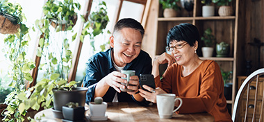 Happy Asian couple video chatting, staying in touch with their family at home