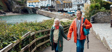 A man and his wife holding hands walking up a hill on a footpath