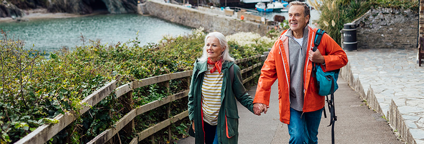 A man and his wife holding hands walking up a hill on a footpath