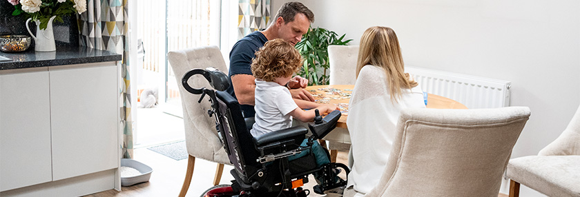 Boy in wheelchair doing jigsaw with parents