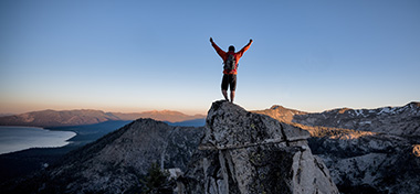Person celebrating making personal goal reaching top of the mountain