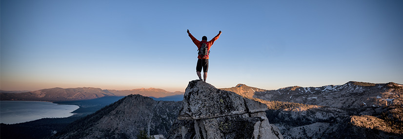 Person celebrating making personal goal reaching top of the mountain