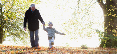 Grandfather walking outdoors with grandson in autumn