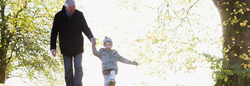 Grandfather walking outdoors with grandson in autumn