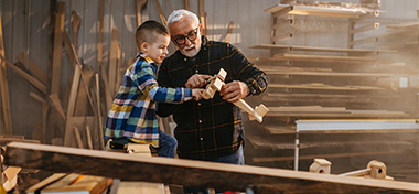 Grandfather making a wooden plane with his grandson 