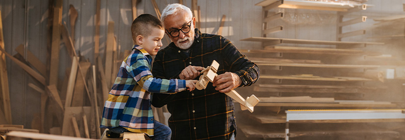 Grandfather making a wooden plane with his grandson 