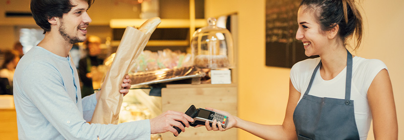 Young man making a contactless payment at a bakery