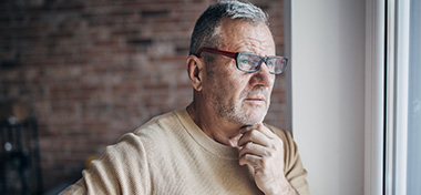 Man looking out of the window looking thoughtful