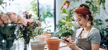 owner of small business flower shop, using smartphone at shop counter