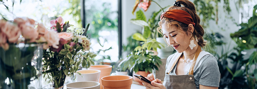 owner of small business flower shop, using smartphone at shop counter