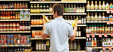 Man deciding which oil to buy in a supermarket
