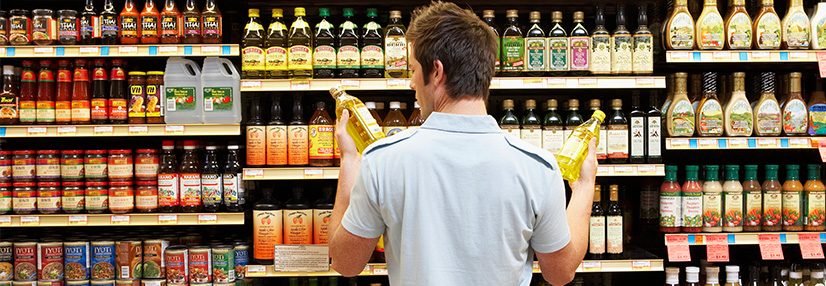 Man deciding which oil to buy in a supermarket