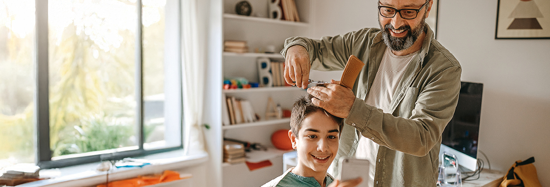 Father cutting son's hair