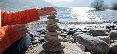 Lady layering stones on top of each other next to the sea