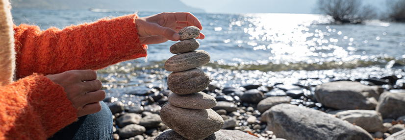 Lady layering stones on top of each other next to the sea