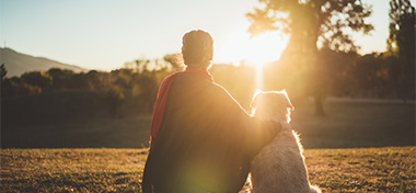 woman with her dog watching the sun set