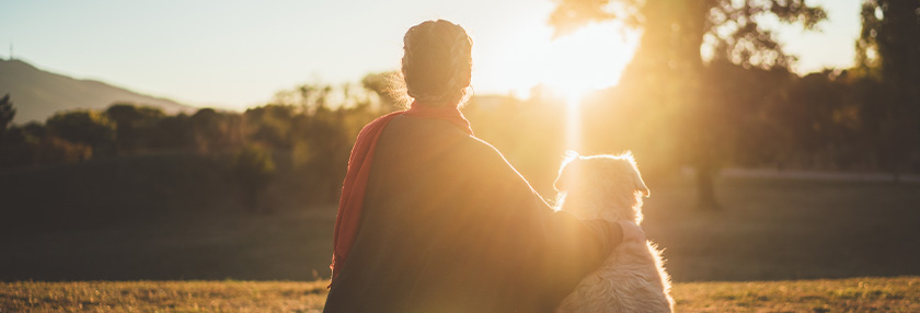 woman with her dog watching the sun set