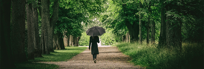 woman holding umbrella walking in the woods