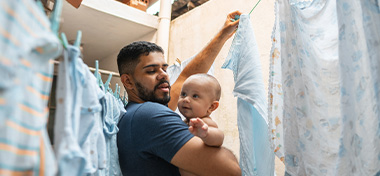 Father holding baby and hanging washing
