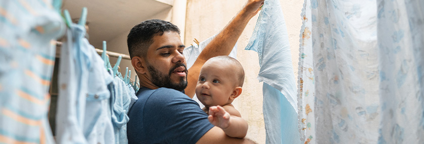 Father holding baby and hanging washing