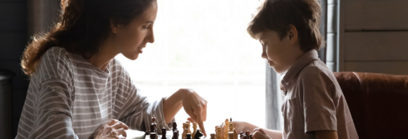 Woman playing chess with young boy