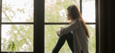 Young woman sitting looking out of window