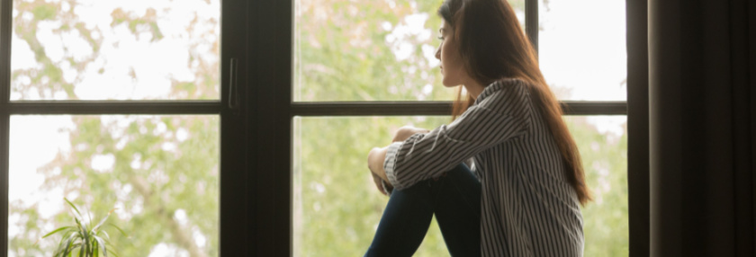 Young woman sitting looking out of window