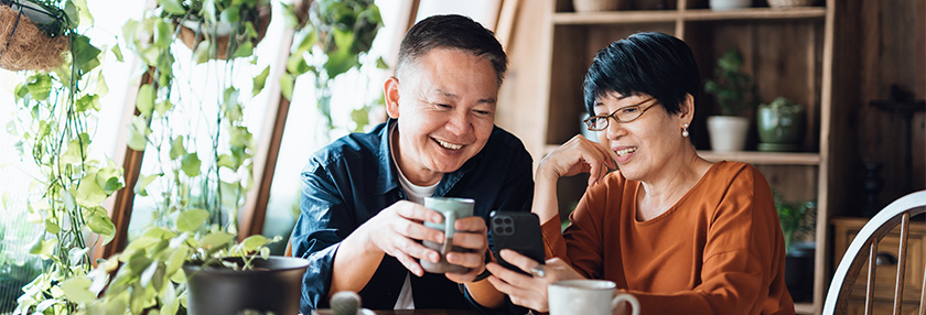 Happy Asian couple video chatting, staying in touch with their family at home