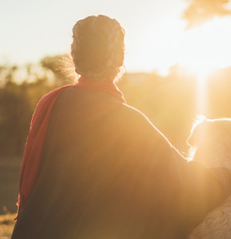 woman with her dog watching the sun set